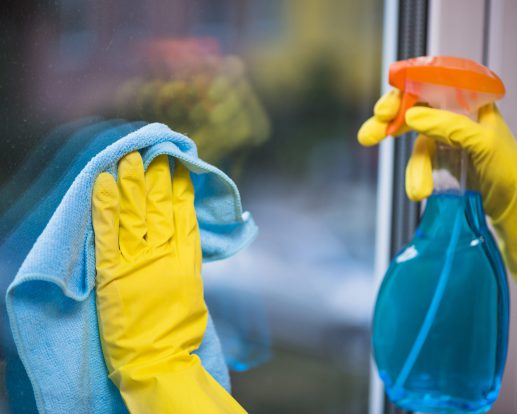 janitor-with-yellow-gloves-cleaning-glass-window